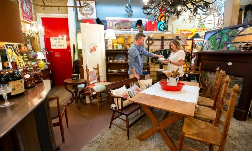 Couple looking at stoneware inside Dixieland Relics in Lakeland, FL. Home decor and antique furniture on display throughout room.