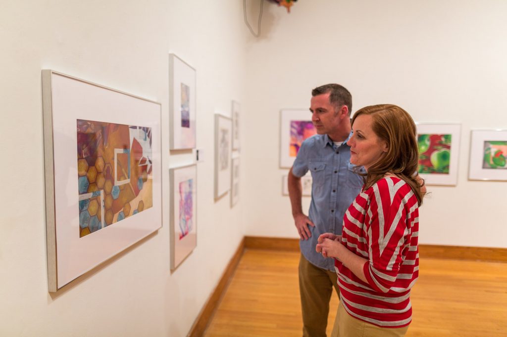 Male and female looking at art hanging in gallery at Polk Museum of Art at Florida Southern College in Lakeland, FL