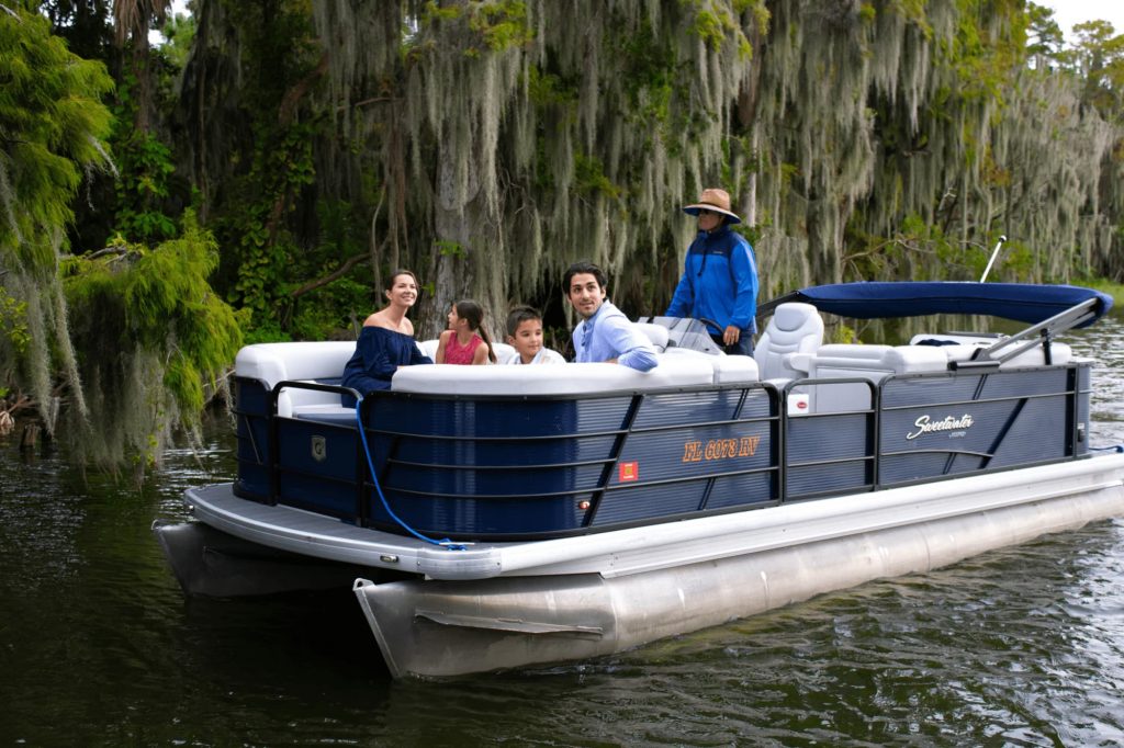 Las cosas para hacer en el agua en Florida Central incluyen: familia de cuatro en un bote pontón durante el recorrido con The Living Water Boat Cruises en Winter Haven, FL
