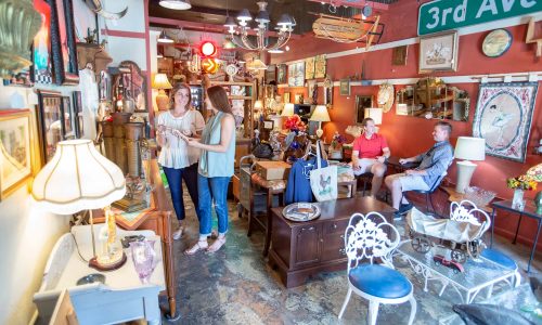 2 people shopping inside The Shop Across the Street in Lakeland, FL. Home decor and antique furniture on display.