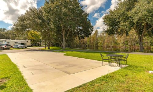 Kissimmee South RV Resort concrete back-in pad with picnic table and lake views.