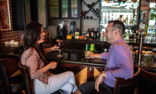 man and woman with cocktails sitting at bar inside Ave Bar in Winter Haven, FL