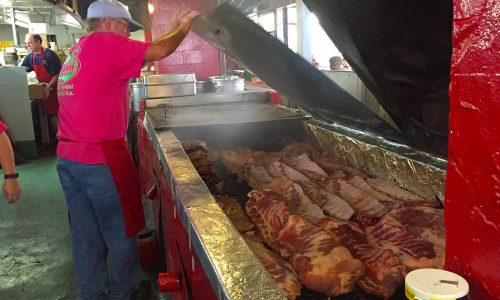 Man looking at racks of ribs cooking inside barbecue pit at Peebles Bar B Que in Auburndale, FL
