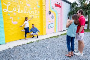Two couples taking photos in front of Lakeland mural. Visitor Services hosts tourism training sessions for residents who enjoy sharing information about things to do in Polk County.