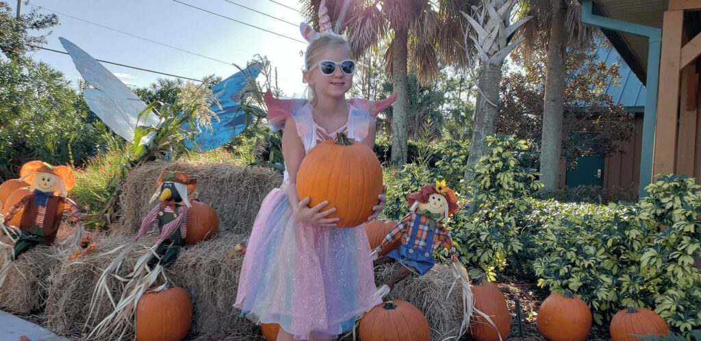 child holding pumpkin outside of Central Florida Visitor Information Center during Ghosts, Goblins, & Goodies - an annual Halloween and fall festival event