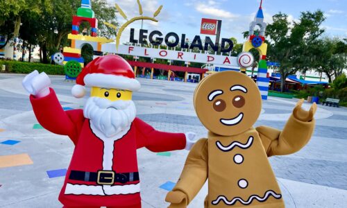 LEGO Santa and LEGO Gingerbread man standing outside LEGOLAND Florida Resort main entrance.