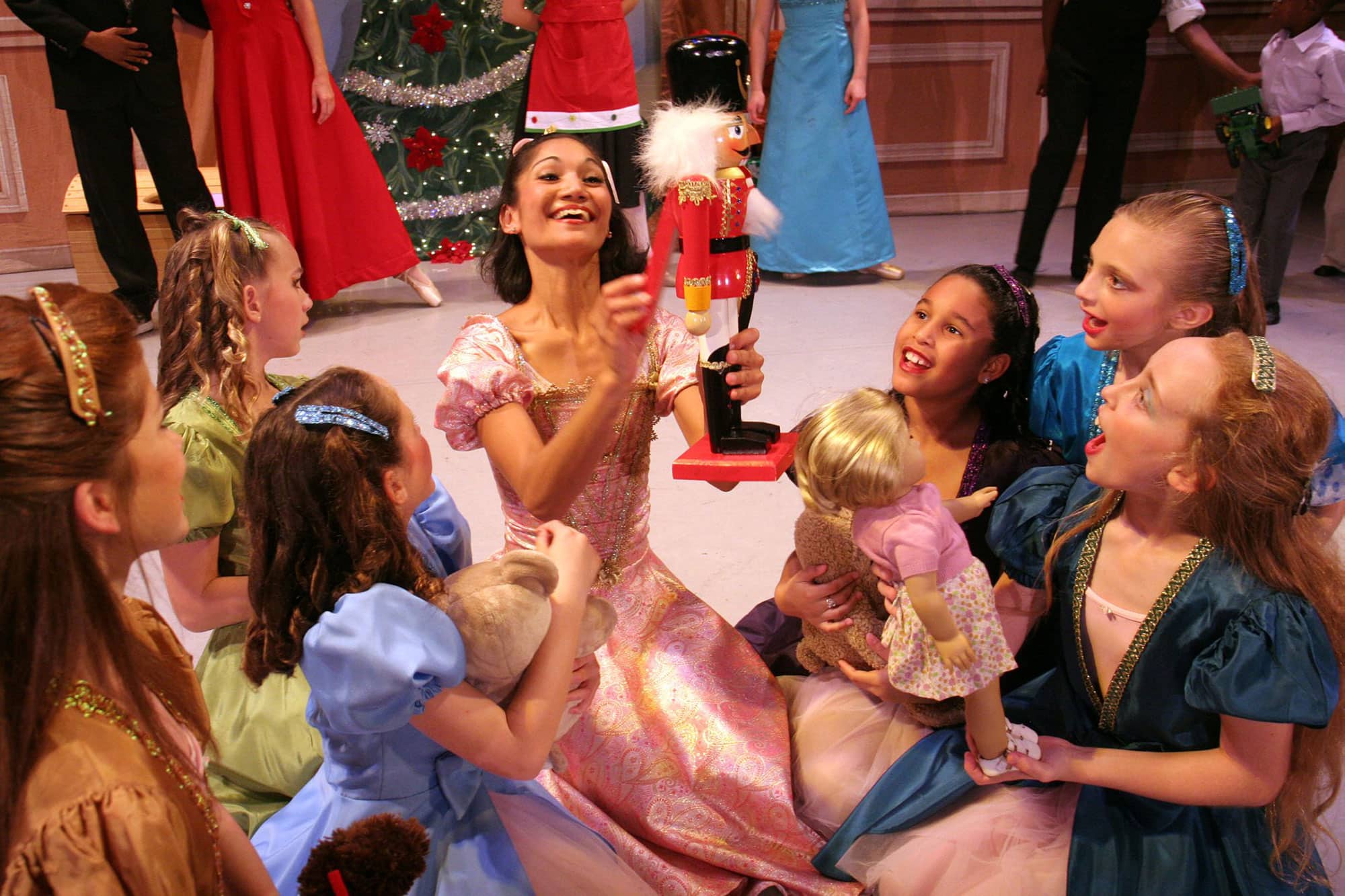 female ballet dancers sitting while one holds up a Christmas Nutcracker during Nutcracker Spectacular