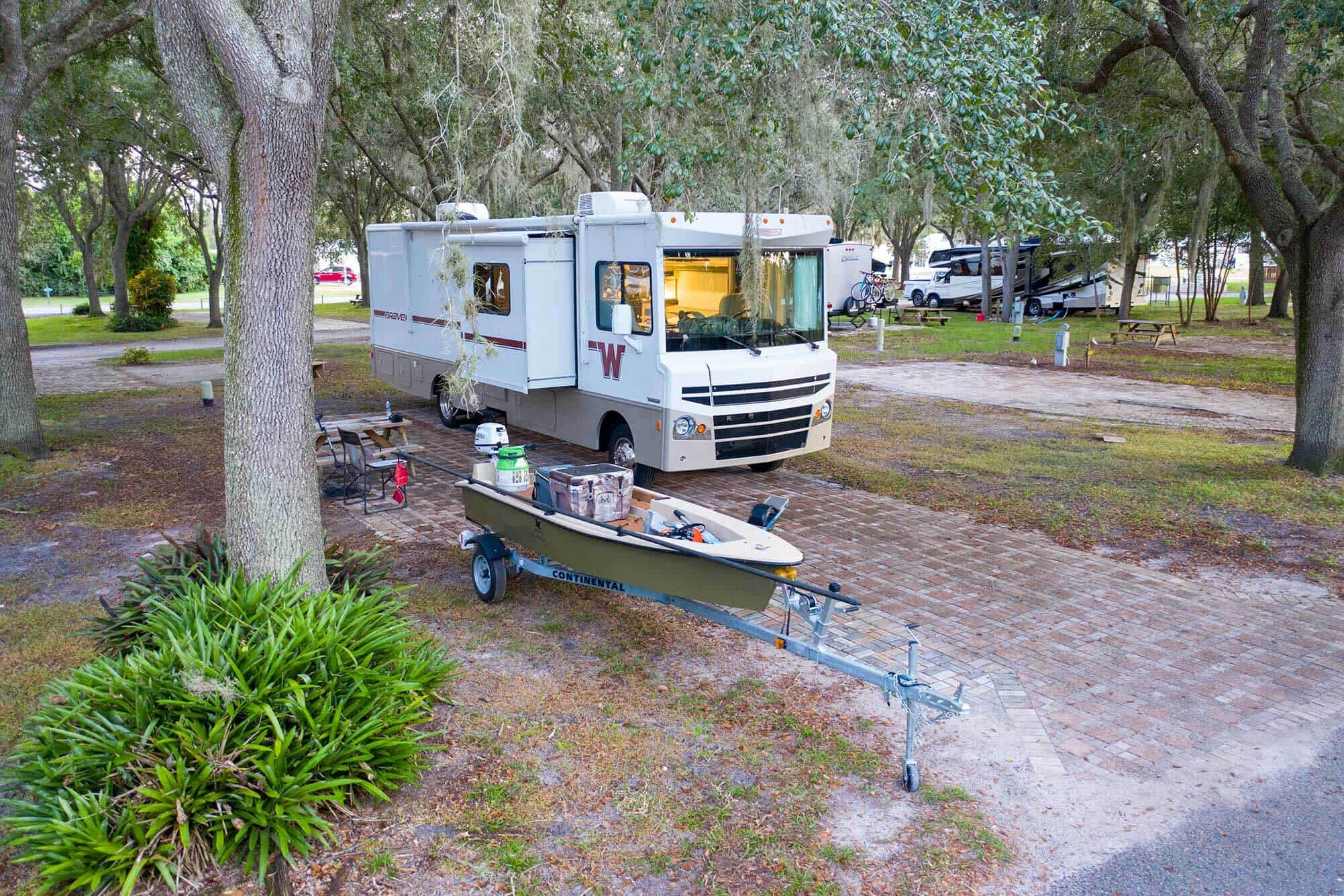Motorhome and boat under an oak tree at Camp Mack, a Guy Harvey Resort, RV campsite near Lake Wales, FL