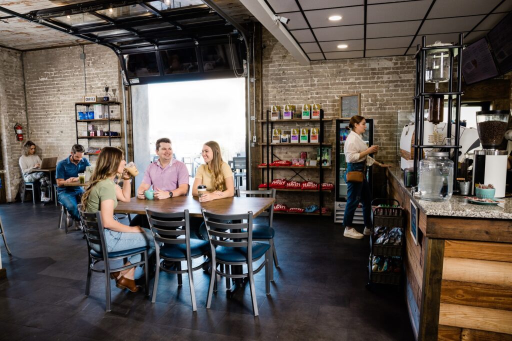 3 people sitting at a table at Haven coffee enjoying coffee.