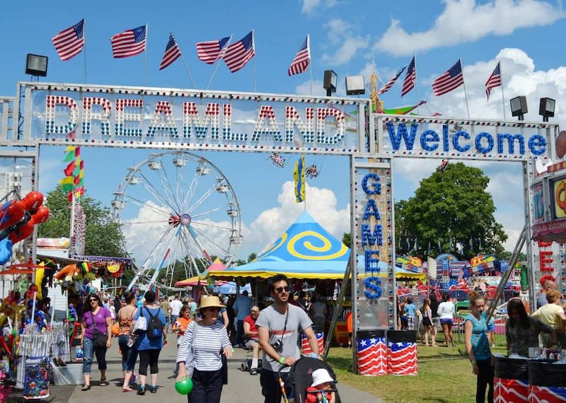 People walking through the Carnival at Eagle Lake with amusements in background