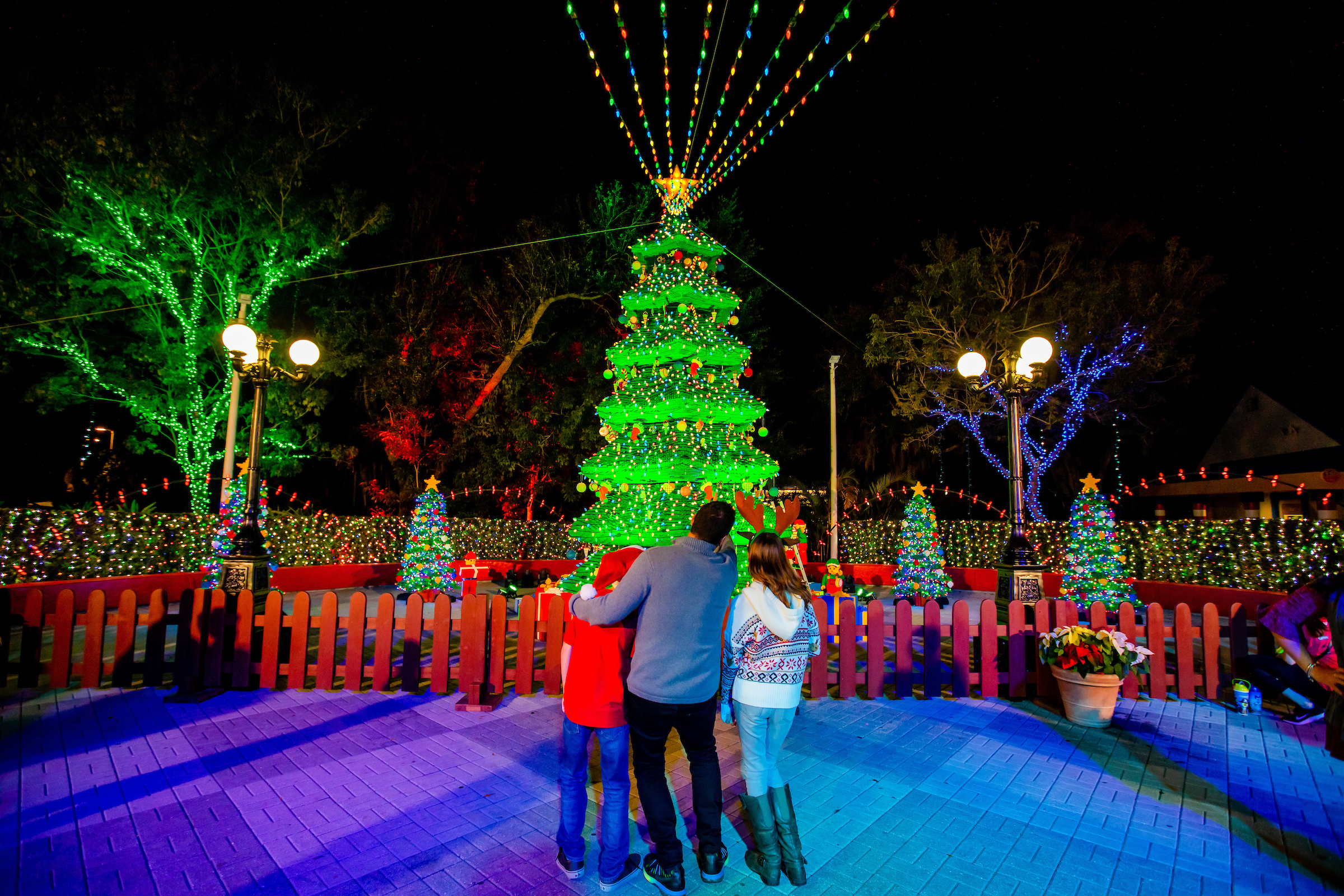 Family standing in front of a LEGO Christmas tree at LEGOLAND Florida's holiday light display.