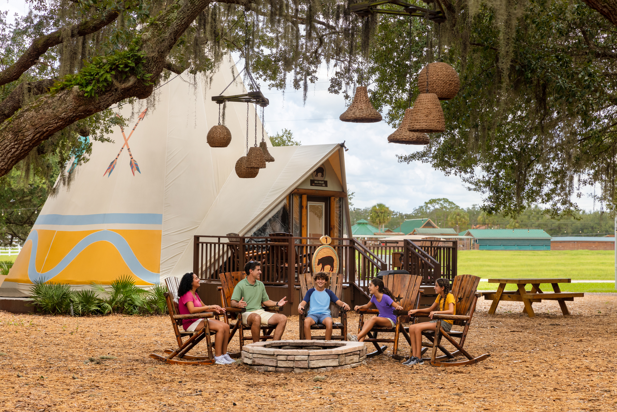 Family at fire pit in front of luxe teepee at Westgate River Ranch Resort