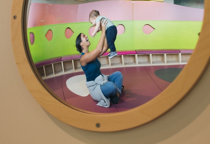 Mom holding up baby reflected in mirror at the Florida Children's Museum